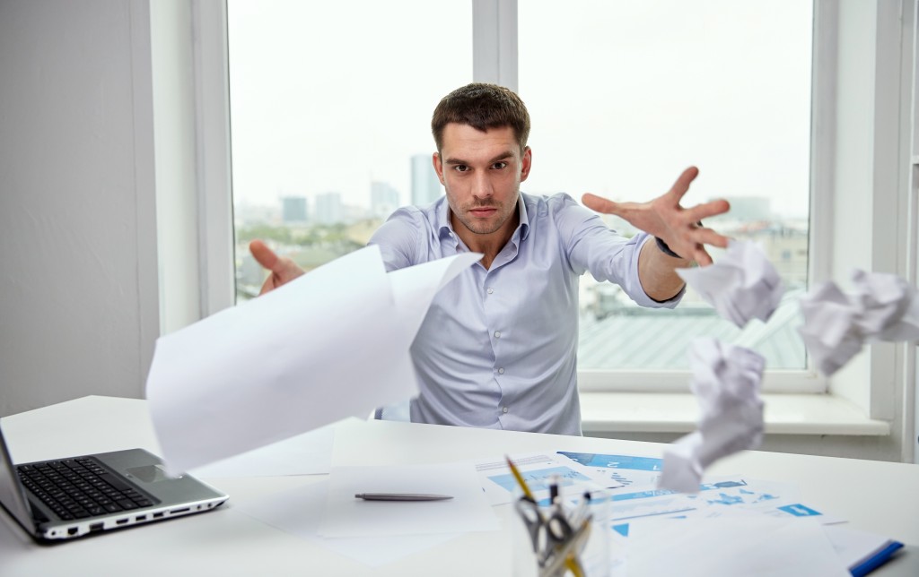 business, people, stress, emotions and fail concept - angry businessman throwing papers in office